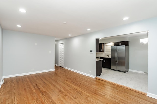 unfurnished living room featuring sink and light hardwood / wood-style flooring