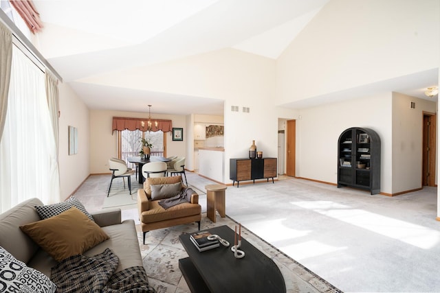 carpeted living room with high vaulted ceiling and an inviting chandelier