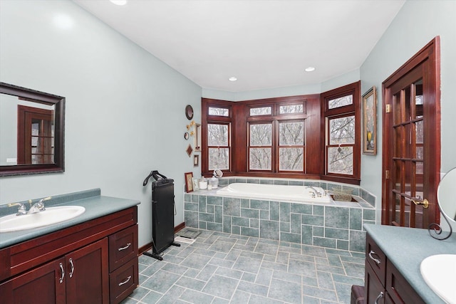 full bathroom featuring a bath, vanity, and baseboards