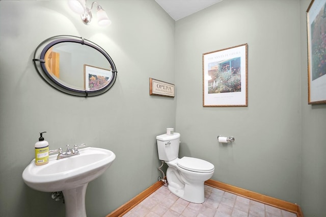 half bathroom with baseboards and toilet