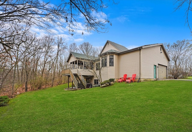back of property with stairway, a garage, a deck, and a yard