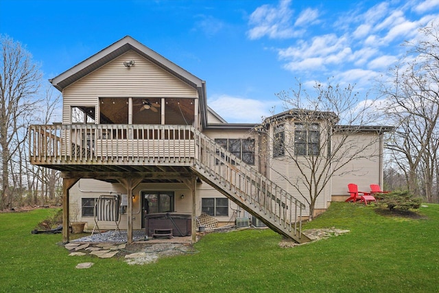 rear view of property with a hot tub, a sunroom, a ceiling fan, a lawn, and stairway