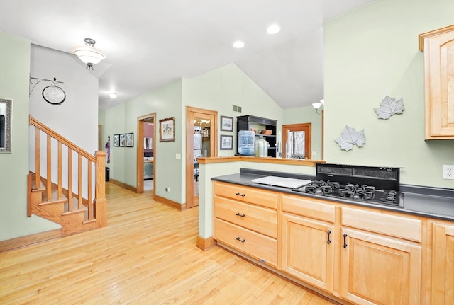 kitchen featuring light brown cabinetry, light wood-type flooring, dark countertops, vaulted ceiling, and recessed lighting