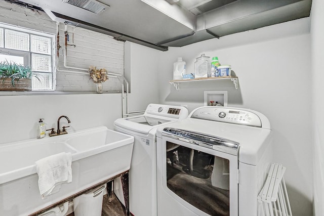 laundry area with laundry area, washing machine and dryer, visible vents, and a sink