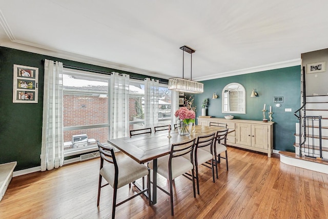 dining space featuring light wood finished floors, baseboards, stairway, and crown molding