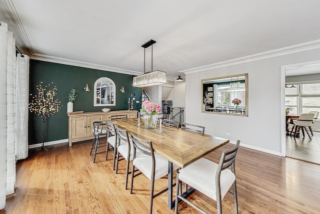 dining area with ornamental molding, light wood-type flooring, baseboards, and stairs