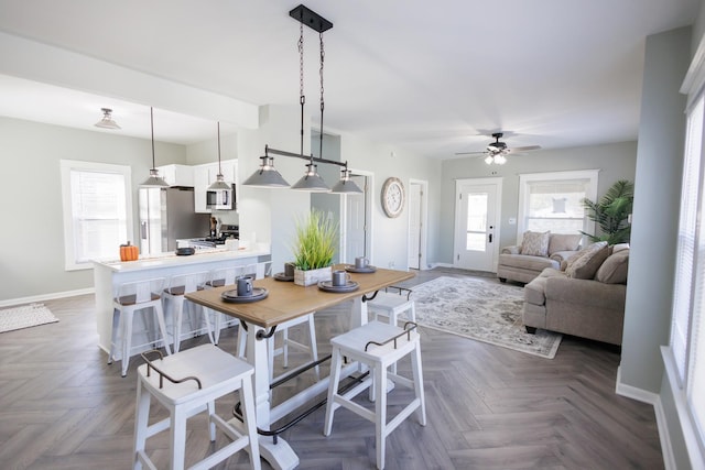 dining space with a wealth of natural light, dark parquet floors, and ceiling fan