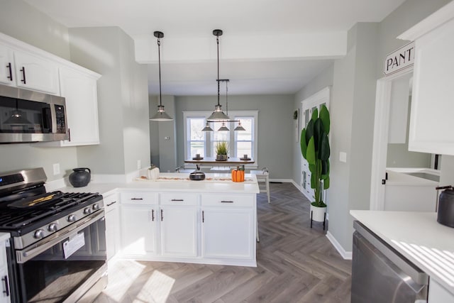 kitchen featuring appliances with stainless steel finishes, hanging light fixtures, white cabinets, kitchen peninsula, and light parquet flooring