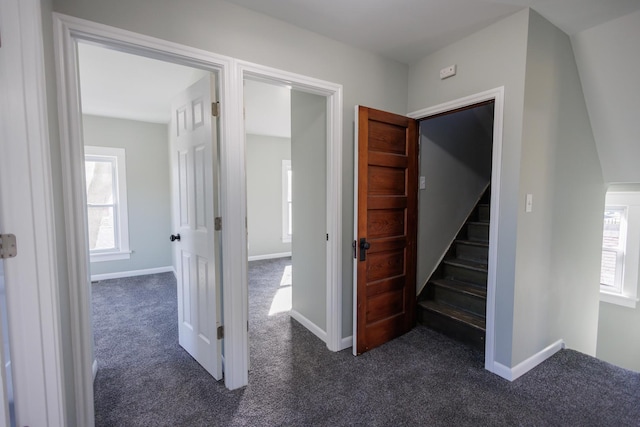 hallway with plenty of natural light and dark colored carpet