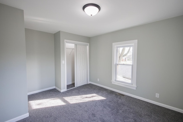 unfurnished bedroom with a closet and dark colored carpet