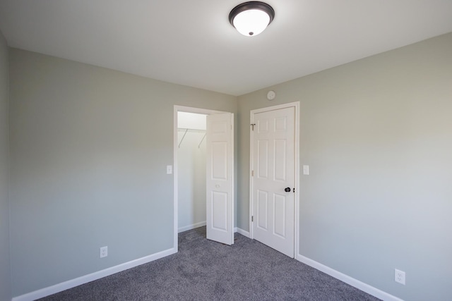 unfurnished bedroom featuring a closet and dark colored carpet