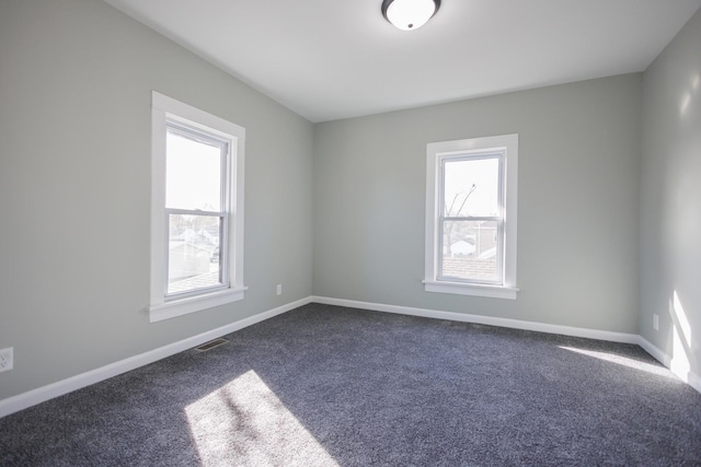 unfurnished room with dark carpet and plenty of natural light