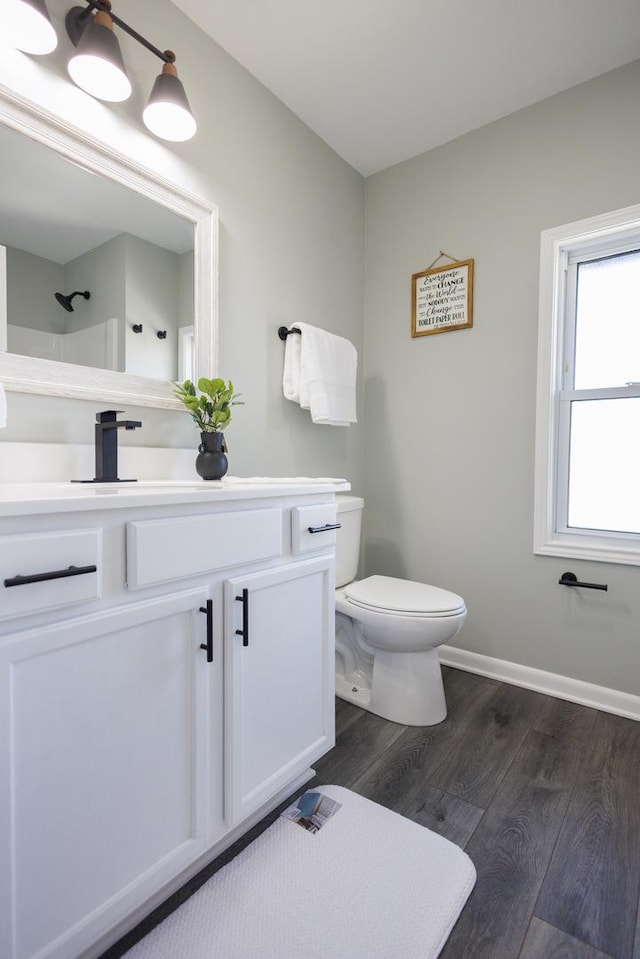 bathroom with walk in shower, vanity, toilet, and wood-type flooring