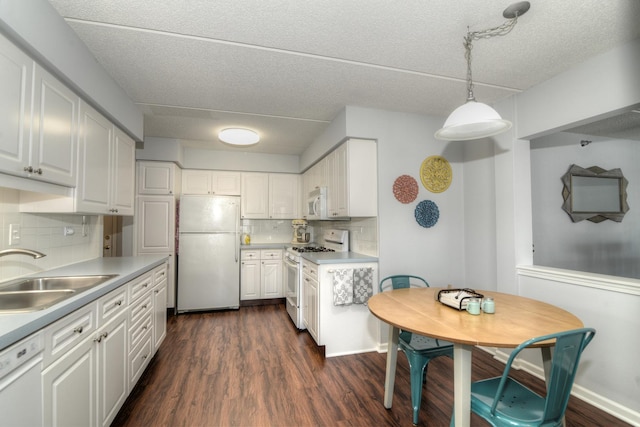 kitchen with pendant lighting, white appliances, sink, and white cabinets