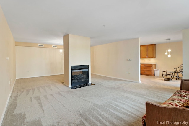 living area with light carpet, a fireplace with flush hearth, visible vents, and baseboards