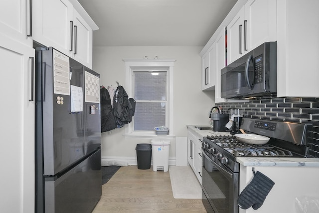 kitchen with white cabinetry, light wood-type flooring, range with gas stovetop, sink, and backsplash