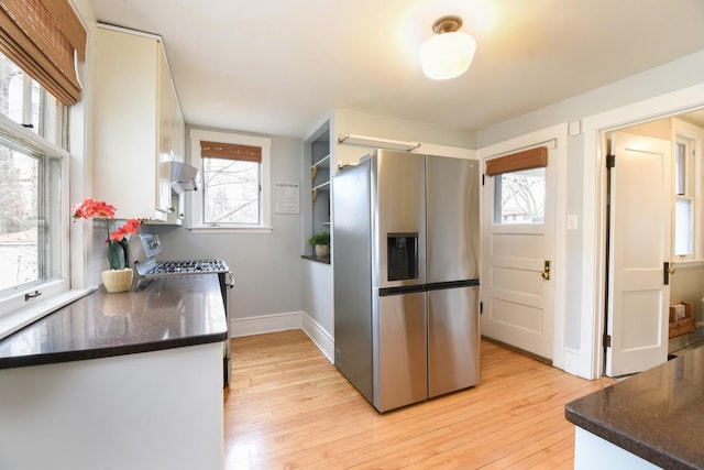 kitchen featuring stainless steel appliances, dark countertops, and light wood-style floors