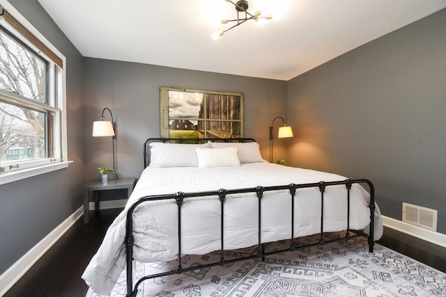 bedroom featuring visible vents, baseboards, and wood finished floors