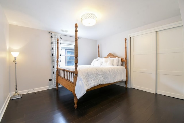 bedroom featuring a closet, visible vents, dark wood finished floors, and baseboards