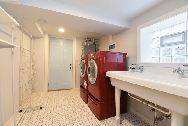 laundry room featuring laundry area, visible vents, water heater, light floors, and washing machine and clothes dryer