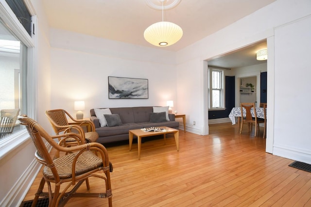 living room with light wood finished floors, visible vents, and baseboards