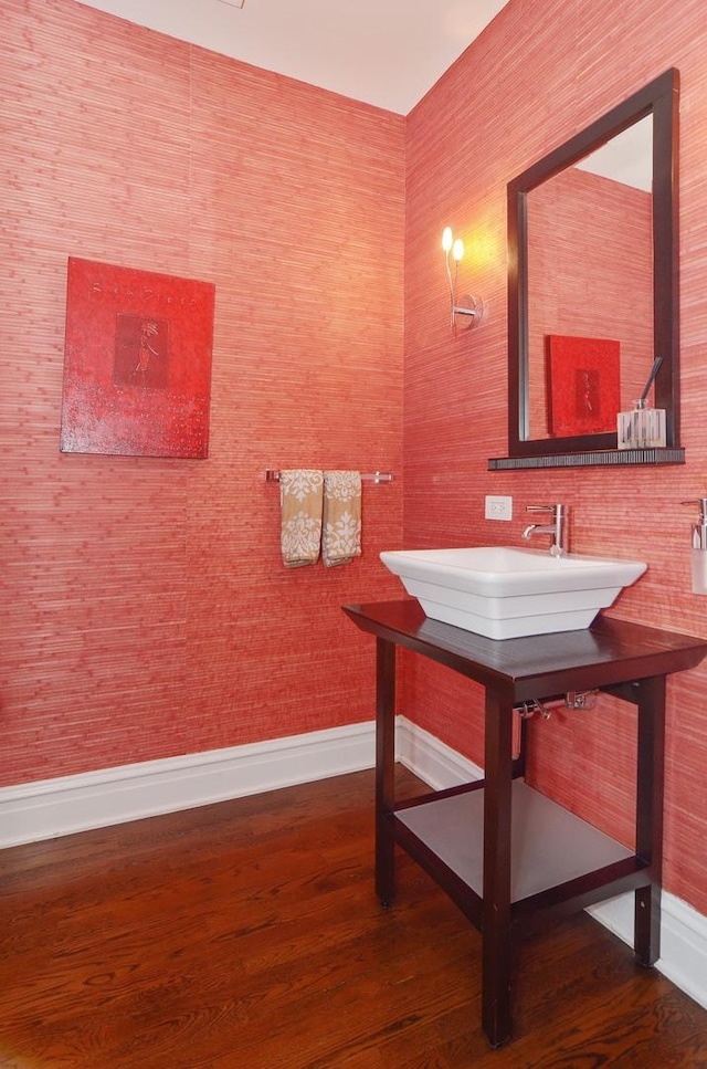 bathroom with baseboards, wood finished floors, and a sink