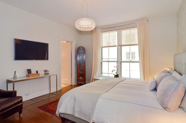 bedroom featuring multiple windows, a chandelier, and wood finished floors