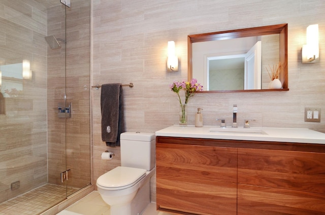 bathroom with tile walls, a shower stall, toilet, and vanity
