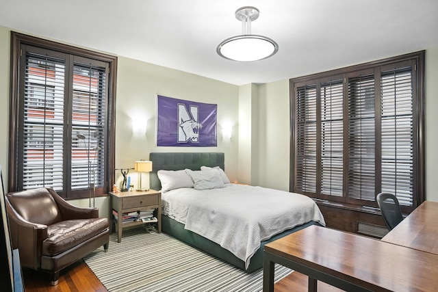 bedroom with an office area and wood finished floors