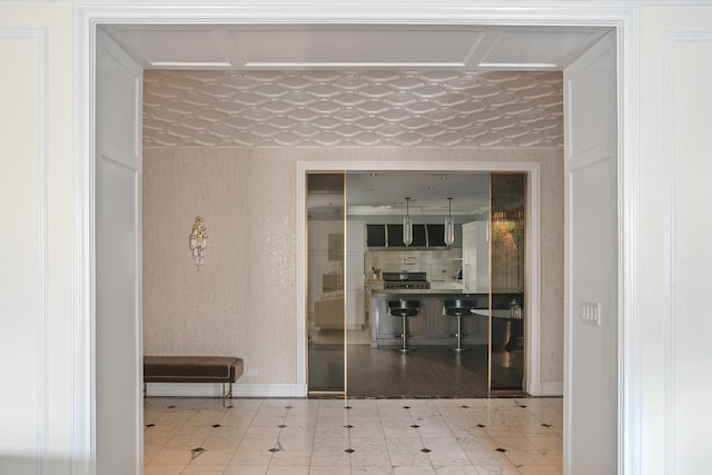 corridor featuring baseboards and wallpapered walls