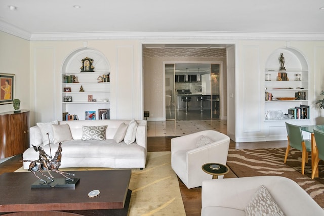 living room with ornamental molding, built in shelves, and wood finished floors
