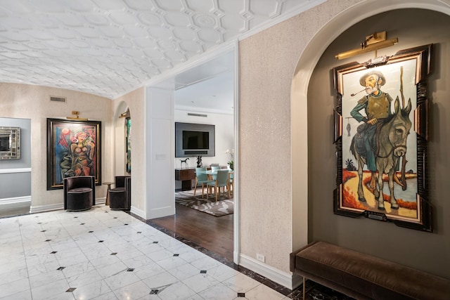 hallway with arched walkways, tile patterned floors, inlaid floor details, and baseboards