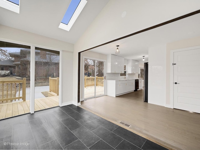 interior space with visible vents, high vaulted ceiling, baseboards, a sink, and dark wood-style floors