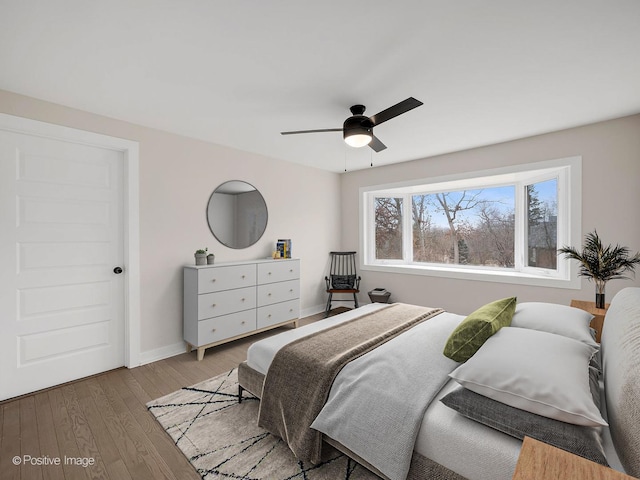 bedroom with baseboards, a ceiling fan, and light wood-style floors