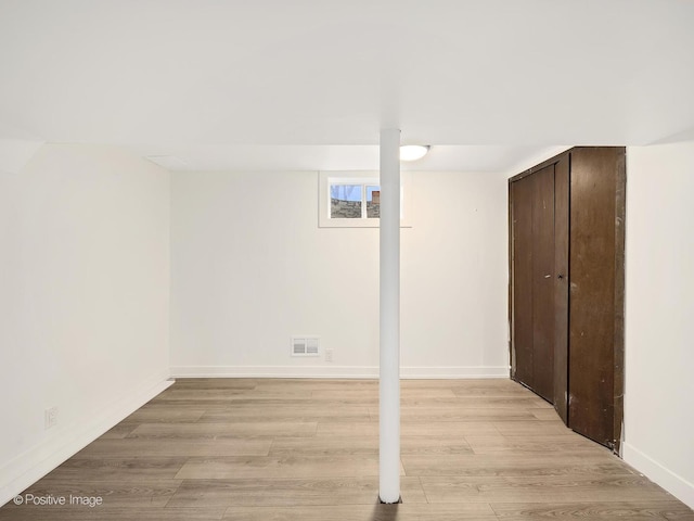 basement with baseboards, visible vents, and light wood-style floors