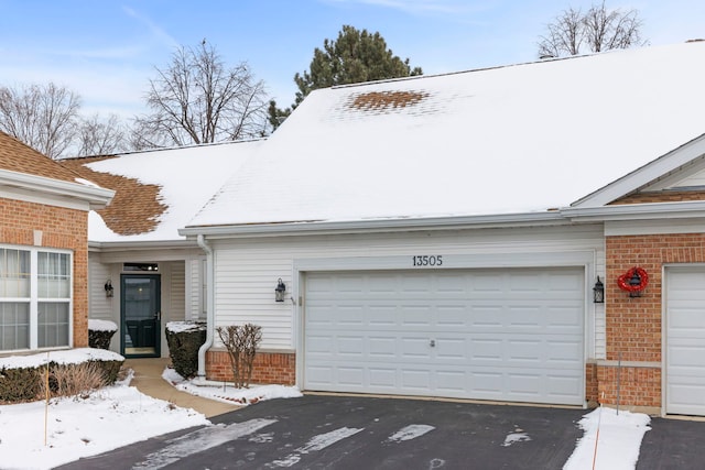 view of front of property featuring brick siding, an attached garage, and aphalt driveway