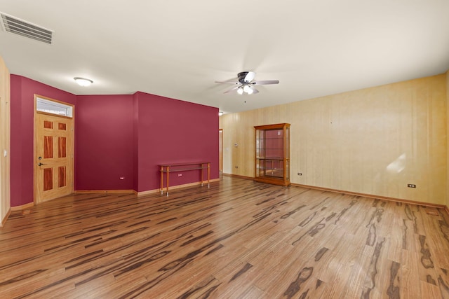 unfurnished room featuring a ceiling fan, visible vents, baseboards, and wood finished floors