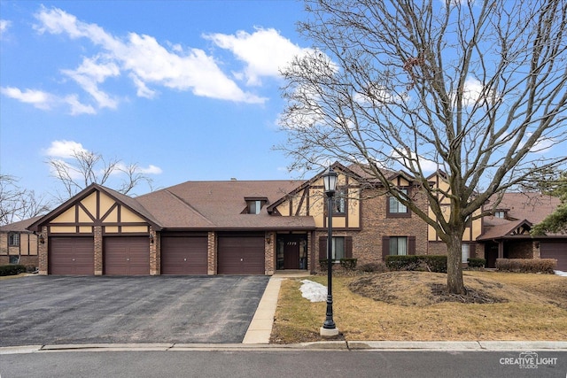 view of front of property featuring an attached garage, roof with shingles, aphalt driveway, and brick siding