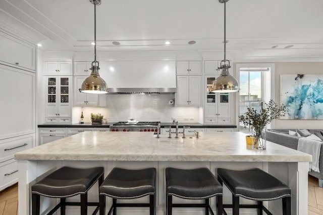 kitchen with sink, a kitchen breakfast bar, white cabinets, and a center island with sink