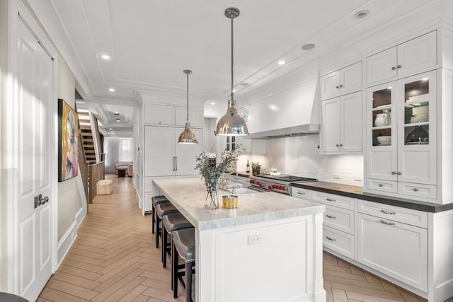 kitchen featuring white cabinetry, wall chimney range hood, and light parquet flooring