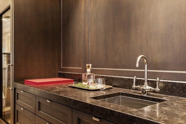 interior space featuring sink, dark brown cabinets, and dark stone counters