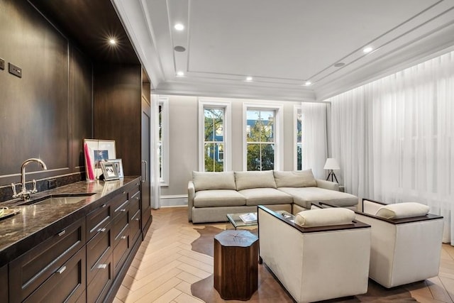 living room with sink, crown molding, and light parquet flooring