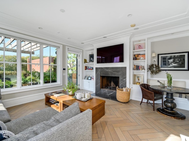 living room featuring built in features, a premium fireplace, and light parquet floors