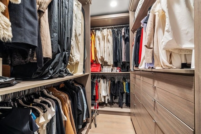 walk in closet with light hardwood / wood-style flooring