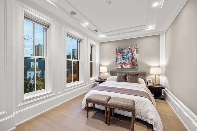 bedroom with a tray ceiling and light hardwood / wood-style floors