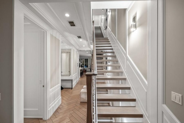 stairs featuring parquet floors and ornamental molding