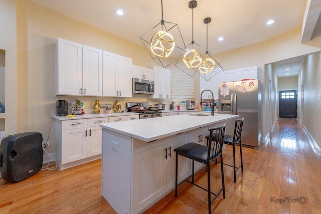 kitchen with stainless steel appliances, white cabinetry, and an island with sink