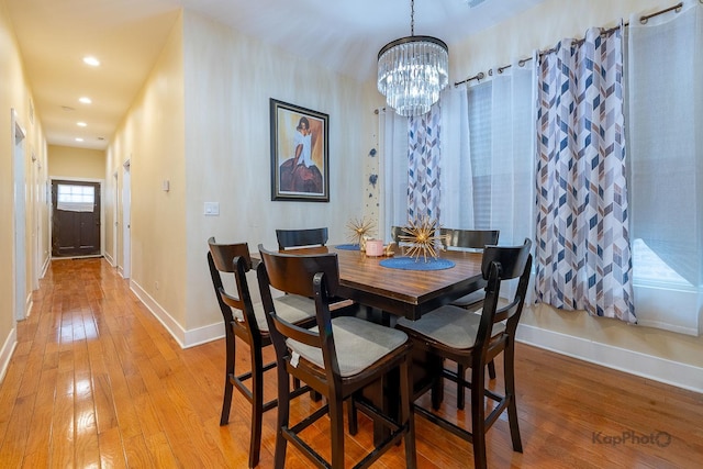 dining space with light wood-type flooring and a notable chandelier