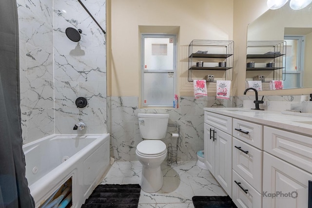 full bathroom with tile walls, tiled shower / bath combo, vanity, and toilet