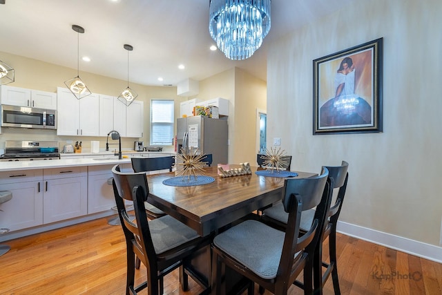 dining room with light wood-type flooring, a chandelier, and sink